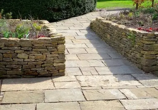 Stone-paved garden path running between planted dry-stone walls